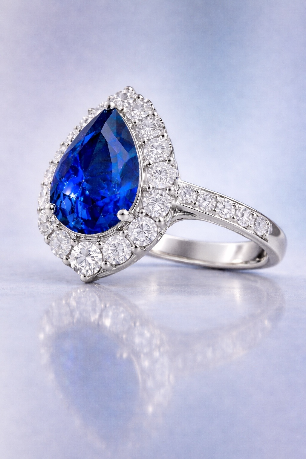 sapphire diamond ring featuring natural blue pear cut sapphire surrounded by brilliant diamond halo side